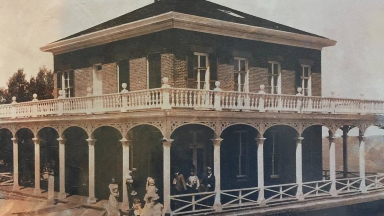 Historic photograph of the Mackay Mansion veranda in Virginia City, Nevada, with visitors seated beneath its arched colonnade